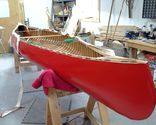 New canvas being trimmed on a red canoe after being filled, primed and painted.